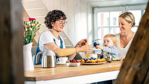twee vrouwen en kind aan eettafel met armprothese