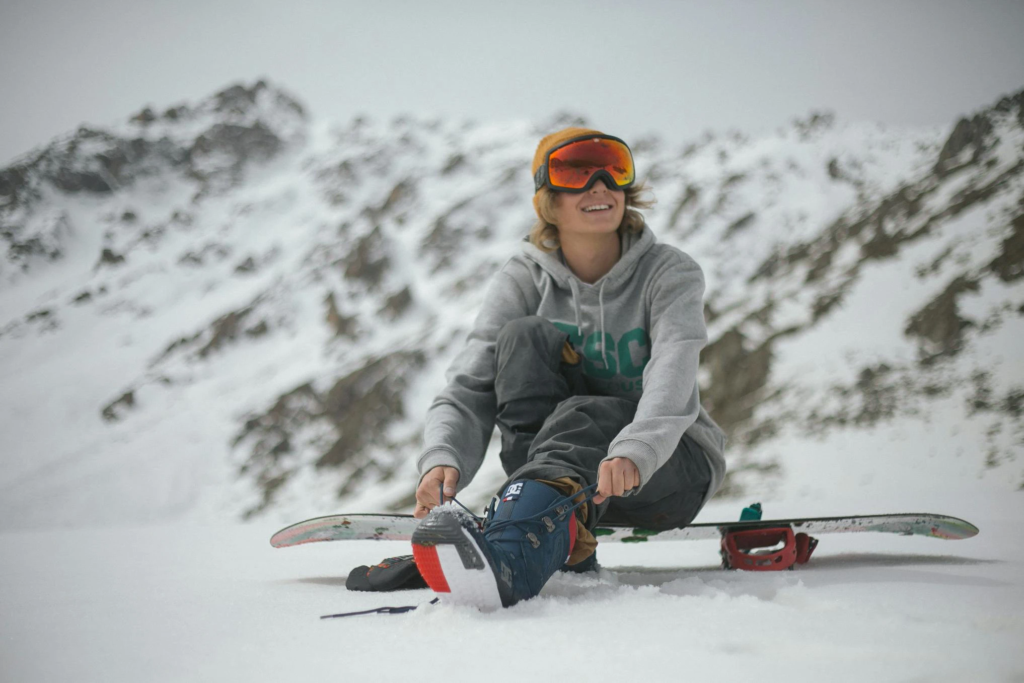 Boy tying his shoe sitting on his snowboard