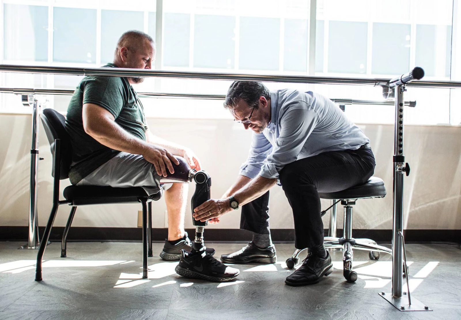 Specialist at Amputee Care Center carefully adjusting and reviewing a leg prosthesis together with the patient.