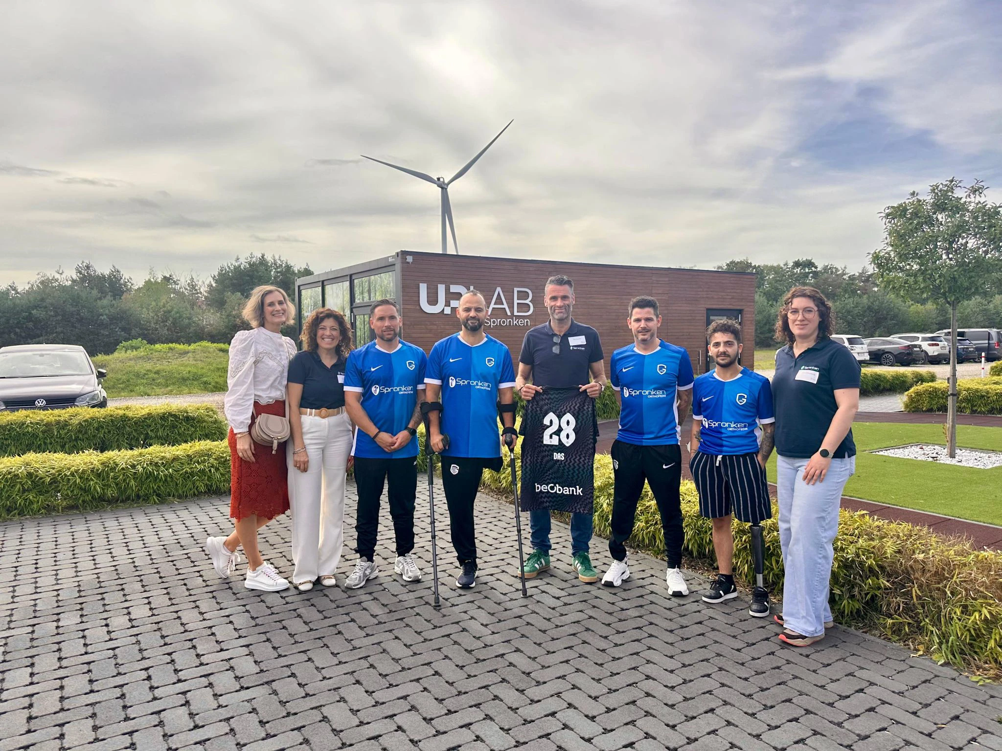 Medewerkers van Amputee Care Center by Spronken Orthopedie in Genk met spelers van het AMP football Team van KRC Genk, inclusief shirtjes.